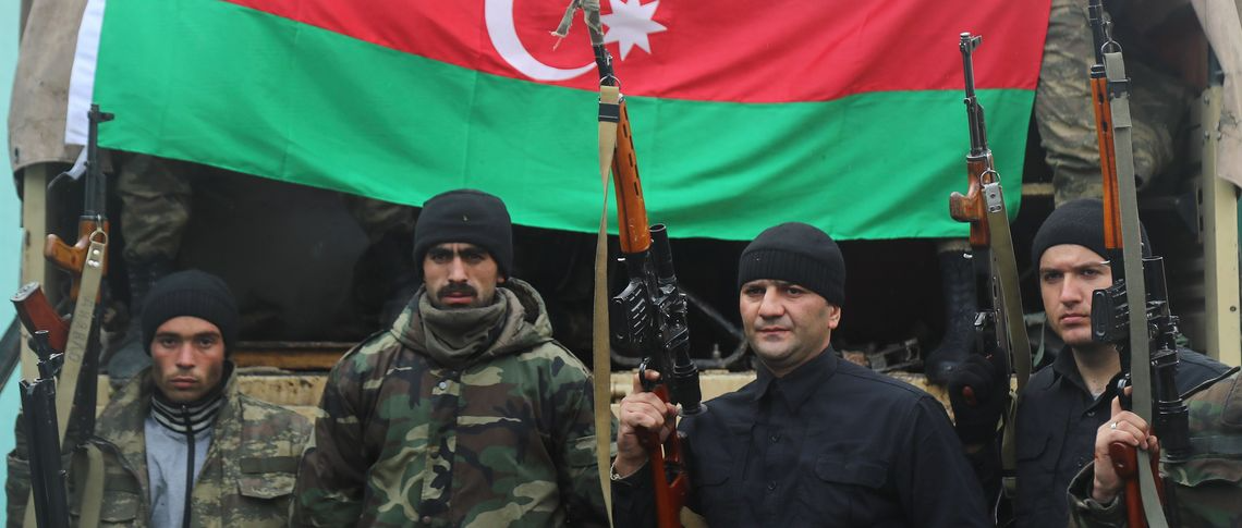 Soldiers in camouflage standing in front of the flag of Azerbaijan.