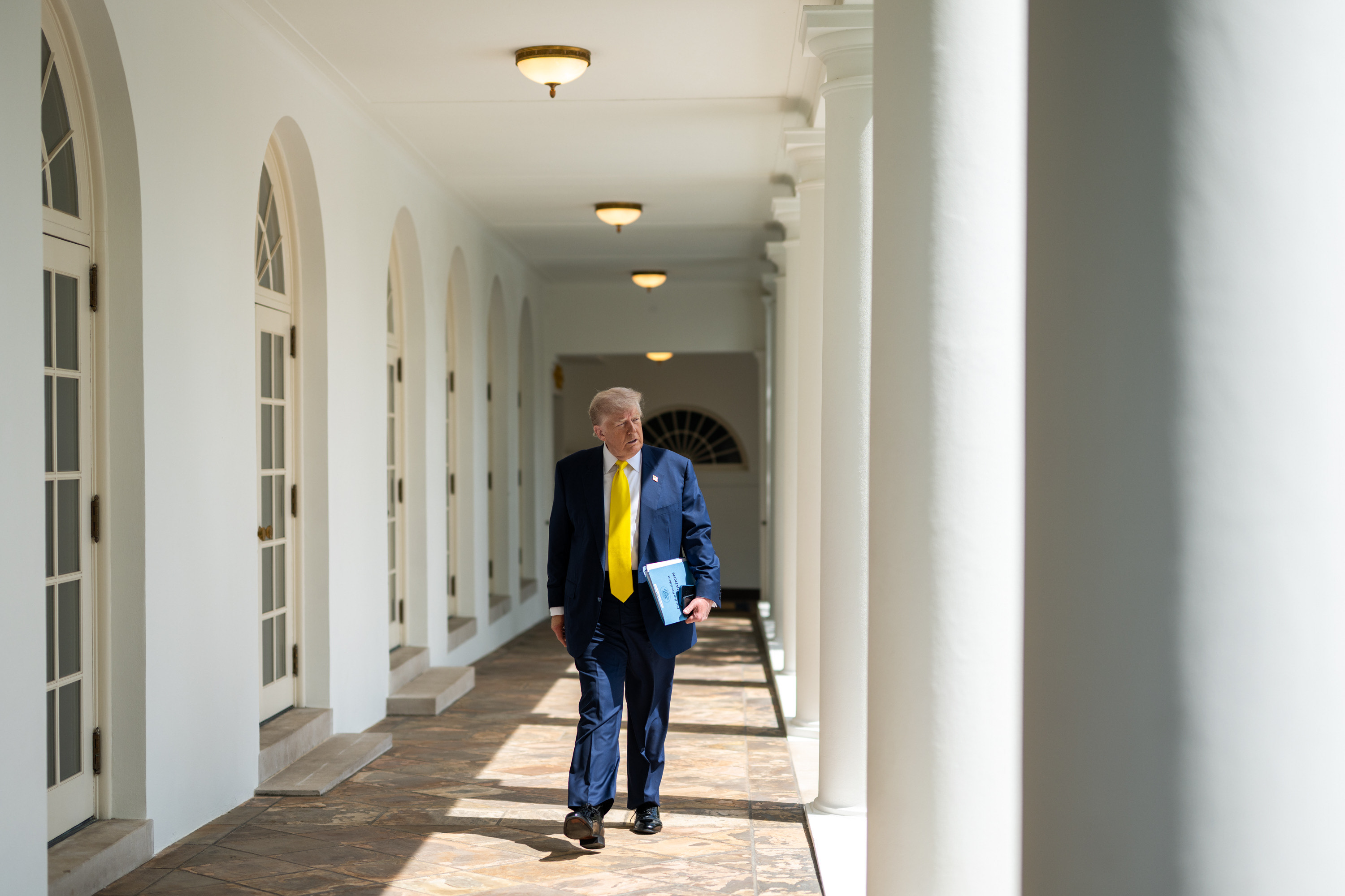 Donald Trump walking along a colonnade at the White House.